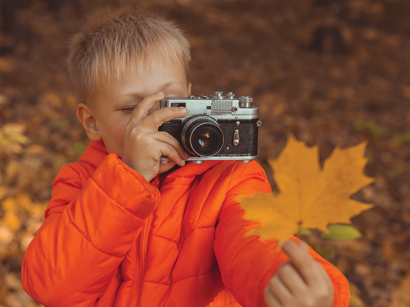A boy taking a photo of a leaf with an old-fashioned camera